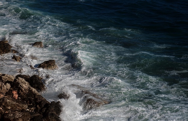 Fondo de ola oceánica rompiendo agua de mar costa rocosa