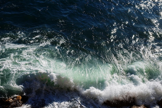 Fondo de ola oceánica rompiendo agua de mar costa rocosa