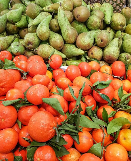 Fondo orgánico vertical de frutas tropicales, mandarinas maduras y peras verdes