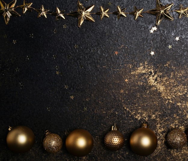 Fondo oscuro con adornos navideños dorados y estrellas, un lugar para texto o saludos de año nuevo