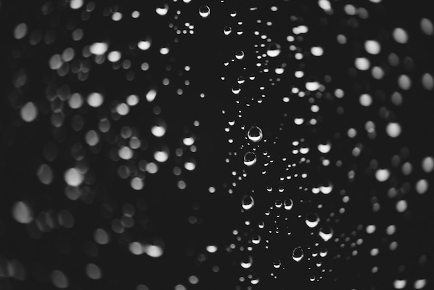 Fondo oscuro monocromo atmosférico con gotas de lluvia en bokeh