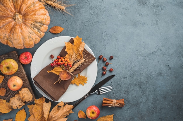 Fondo de otoño culinario festivo con un plato blanco hojas de otoño y una calabaza