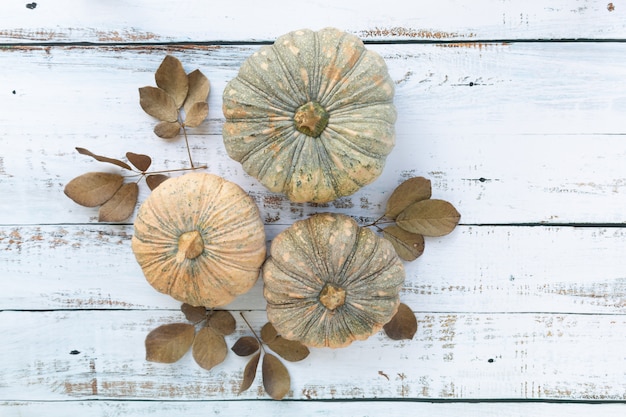 Foto fondo de otoño y día de acción de gracias de hojas caídas y frutas de calabazas en la mesa de madera