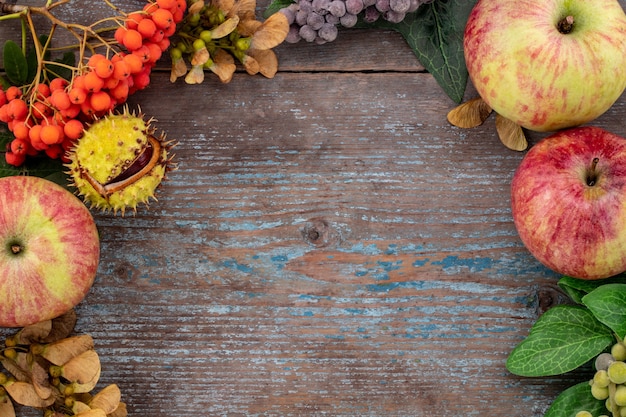 Fondo de otoño de hojas caídas y frutas con lugar vintage en mesa de madera vieja. Concepto de día de acción de gracias.