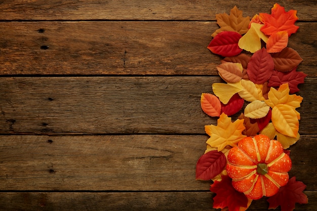 Fondo de otoño con hojas y calabazas en madera oscura.