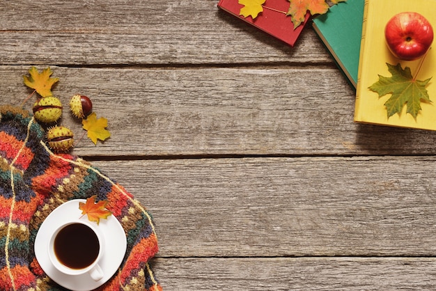 Fondo de otoño rojo, hojas verdes y amarillas, manzanas con una taza de café o té con libros