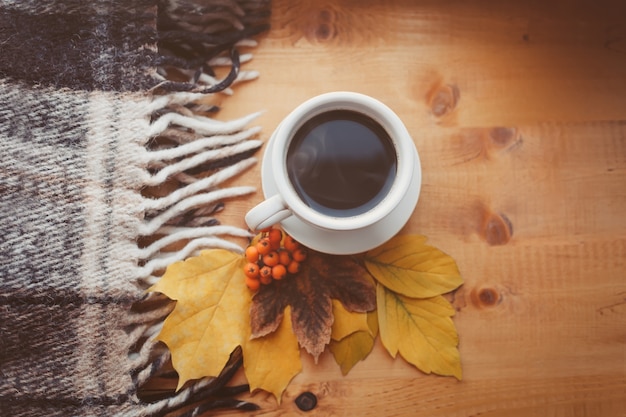 Fondo de otoño Una taza de café caliente, hojas amarillas de otoño sobre una superficie de madera