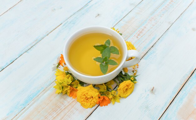 Fondo de otoño. Taza de té con menta y flores de otoño sobre un fondo de madera. Concepto Otoño Tiempo Otoño