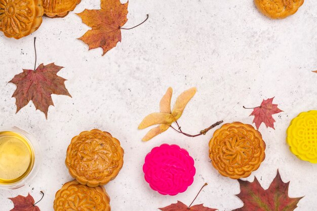 Fondo de otoño con tortas de luna tradicionales chinas y hojas de arce de otoño. Tarjeta de felicitación del festival de mediados de otoño. Copia espacio