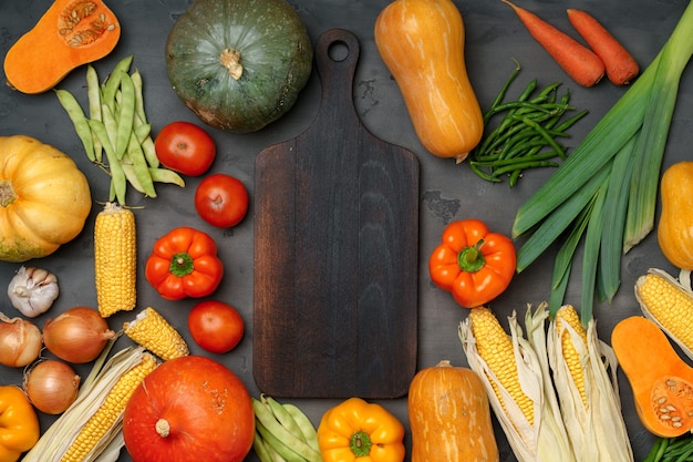 Fondo de otoño con verduras frescas y tabla de cortar de madera