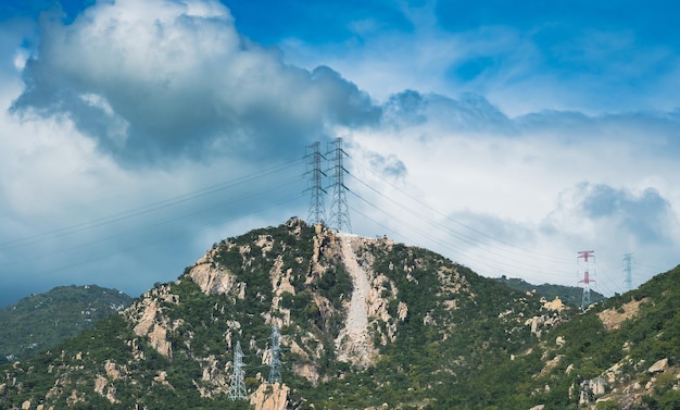 Fondo de paisaje de belleza de naturaleza real Montaña rocosa nublado brillante Cielo azul día de verano alto voltaje Líneas de electricidad pilones Sentimientos de humor de sol Suministro de energía áreas remotas estructuras de ingeniería