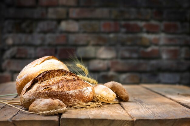 Fondo de panadería. Conjunto de pan crujiente recién horneado y bollos con espigas de trigo en una mesa de madera en una panadería. ÃƒÂ Ã‚Â¡opy espacio