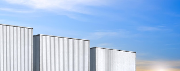 Fondo panorámico de 3 almacenes industriales de metal corrugado contra el cielo azul