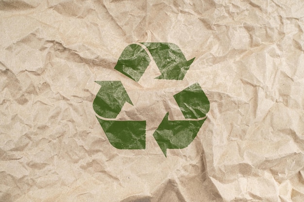 Foto fondo de papel arrugado marrón reciclado de un embalaje de papel con símbolo de reciclaje verde ecología