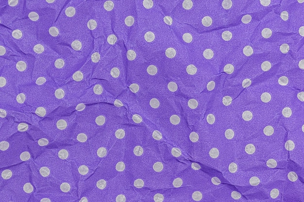 Fondo de papel arrugado púrpura con patrón de lunares blancos.