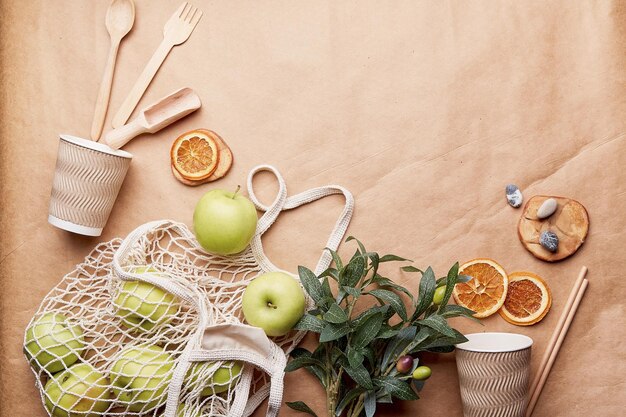 Fondo de papel artesanal natural cubiertos completos de madera tazas de cartón manzanas y naranjas secas concepto ecológico de cero residuos estilo de vida sostenible sin plástico espacio de copia