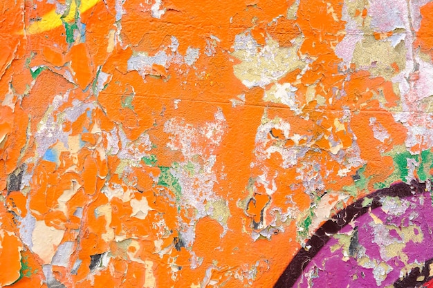 Fondo de pared colorido con pinturas dañadas de naranja