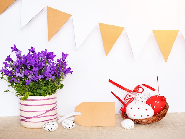 Fondo de Pascua con huevos en nido de pájaro y signo de etiqueta de regalo vacío para mensaje de saludo de Pascua feliz