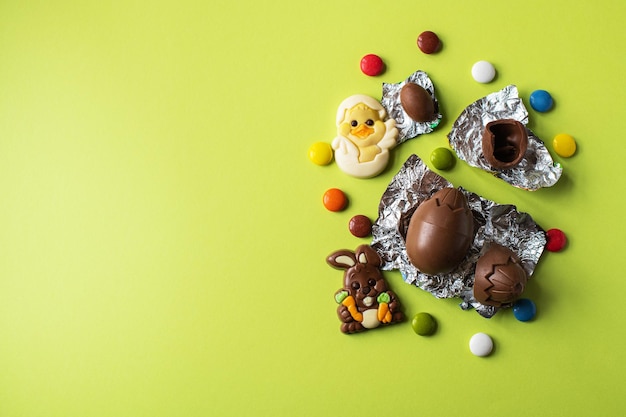 Fondo de Pascua de huevos de Pascua de chocolate y dulces de colores sobre un fondo verde Vista superior y espacio de copia