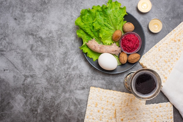 Fondo de Pascua con vino, matza y plato seder en gris.