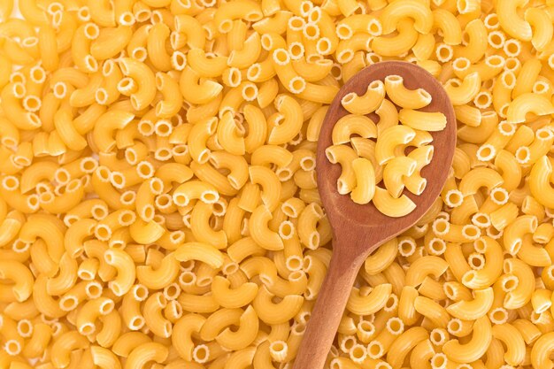 Foto fondo de pasta chifferi rigati cruda con cuchara de madera