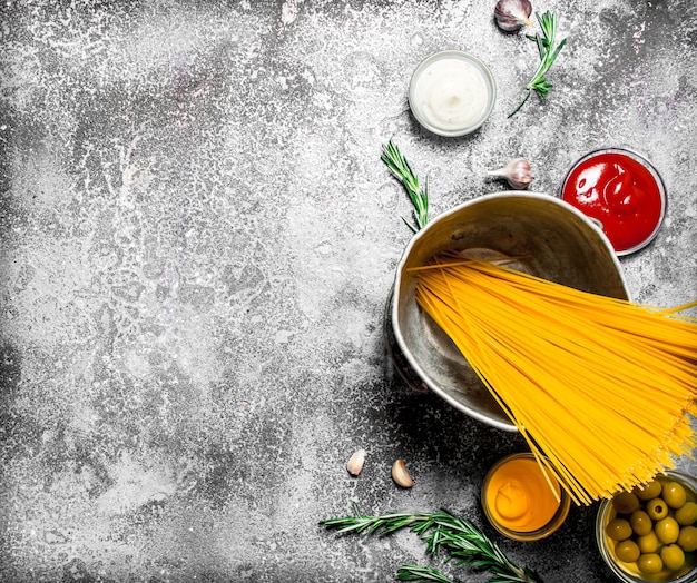 Fondo de pasta espaguetis viejos en la sartén con especias y tomates sobre fondo rústico