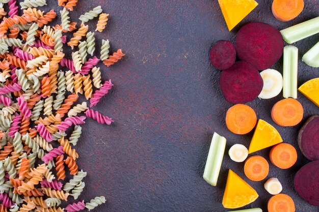 Foto fondo de pasta seca colorida brillante hecha de verduras y sus tintes vegetales naturales apio, remolacha, zanahoria, calabaza, pastinaca. concepto de comida sana