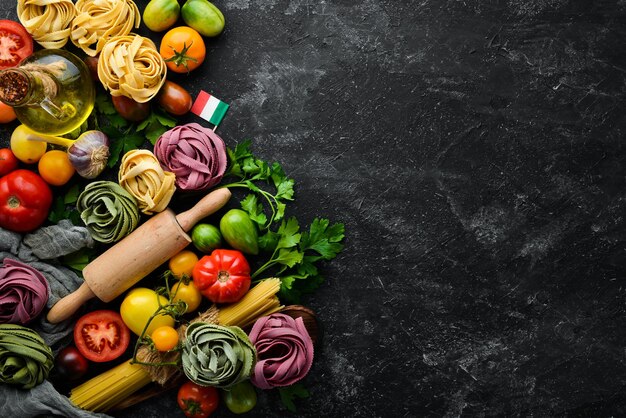 Fondo de pasta tagliatelle de pasta seca e ingredientes sobre fondo negro Vista superior Espacio libre para el texto