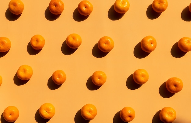 Fondo de patrón de vista superior de naranjas enteras con sombra fuerte sobre fondo naranja