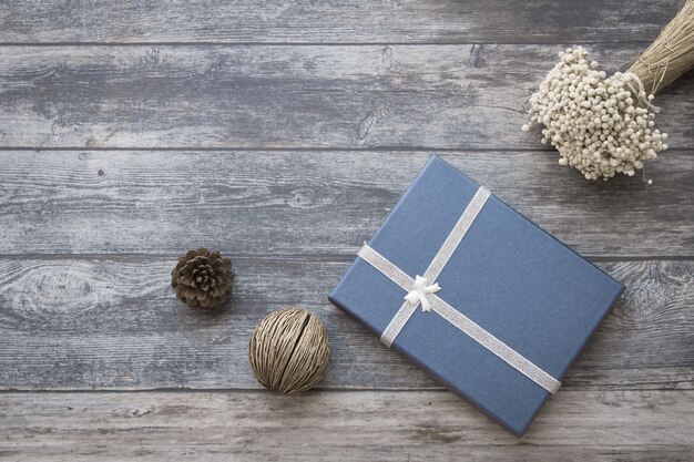 Fondo de piñas secas, paquete de regalo púrpura sobre fondo de mesa de madera.