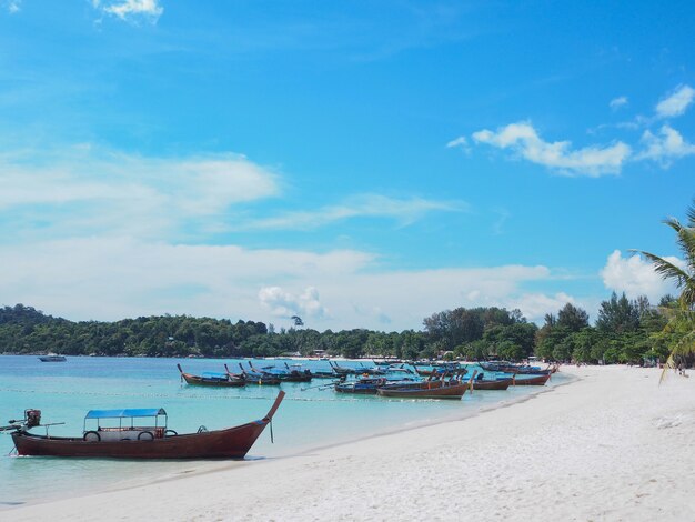 Fondo de playa de verano. Pequeño barco turístico local se encuentra en el mar sobre un cielo azul frente a islas verdes en Koh Lipe, provincia de Satun, Tailandia.