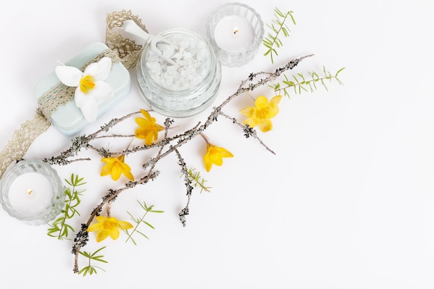 Fondo de primavera suave spa con ramitas y flores amarillas de primavera, velas, sal de spa en blanco