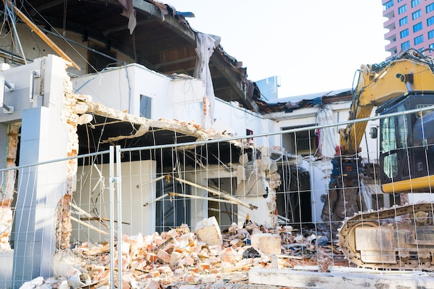 Fondo del proceso de demolición del edificio Excavadora rompiendo casa antigua