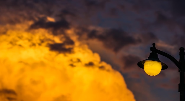 Fondo de una puesta de sol brillante con nubes naranjas y una farola amarilla Foto de alta calidad