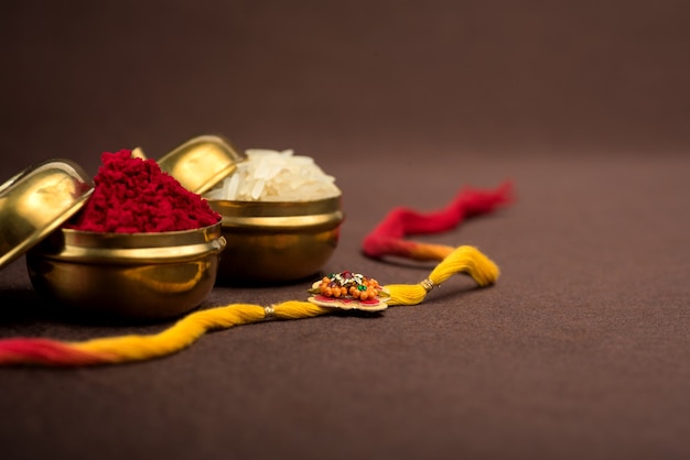 Fondo de Raksha Bandhan con un elegante Rakhi, granos de arroz y Kumkum