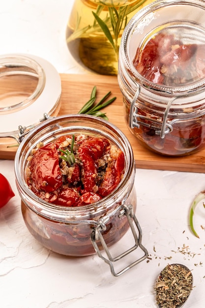 Fondo de receta de comida. Cerrar Tomates secados al sol con ajo, orégano, aceite de oliva en un frasco sobre una mesa de luz.