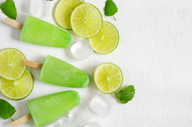 Fondo refrescante con paletas de menta de limón saludable con rodajas de limón fresco y cubitos de hielo. Vista superior