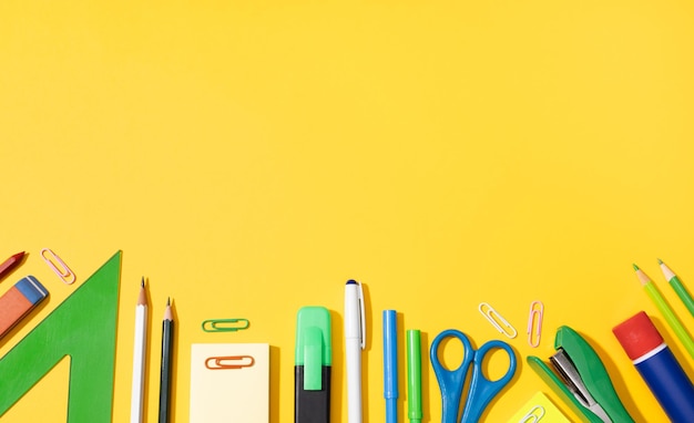 Fondo de regreso a la escuela con espacio de copia Variedad de útiles escolares y de oficina sobre fondo amarillo
