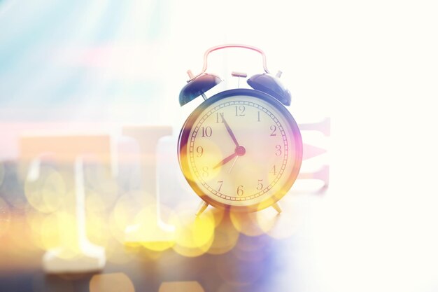 Fondo con un reloj en la mesa y un bokeh en colores pastel del arco iris Tiempo para descansar y viajar