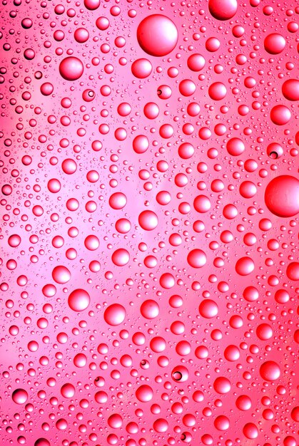 Fondo rojo abstracto. Líquido sobre vidrio. Gotas de agua de colores