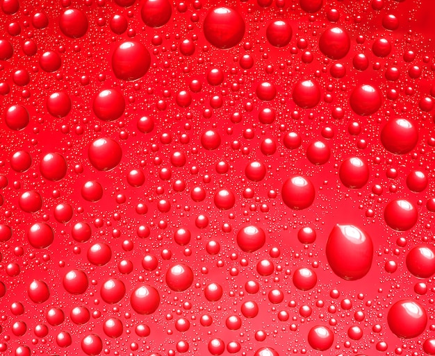 Fondo rojo abstracto. Líquido sobre vidrio. Gotas de agua de colores