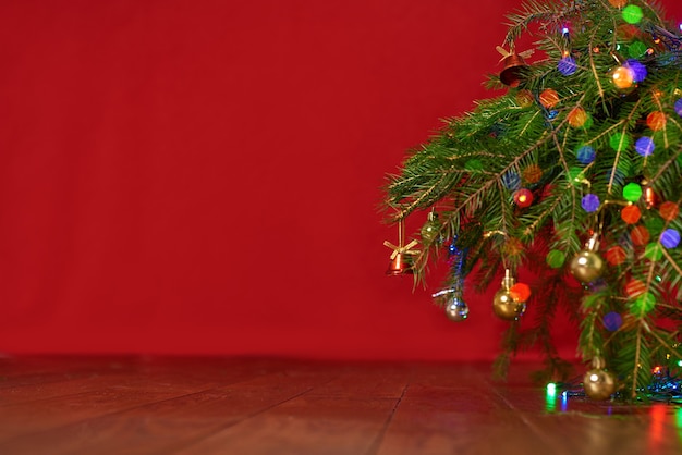 Fondo rojo, árbol de navidad, ramas de abeto con juguetes de año nuevo, fondo para una tarjeta de año nuevo