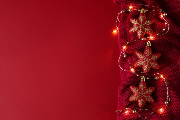 Fondo rojo de Navidad con bolas de juguetes de Navidad rojos y una guirnalda sobre un tejido de punto burdeos