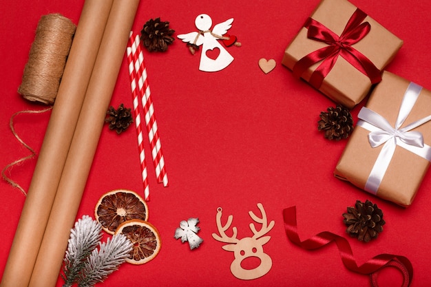 Fondo rojo de Navidad con cajas de regalo, rollos de papel y adornos. Preparación para vacaciones.