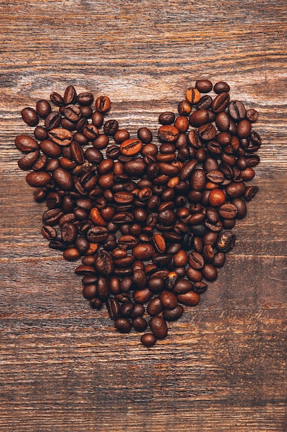 Fondo romántico. Día de San Valentín. Corazón de granos de café en la superficie de madera marrón.