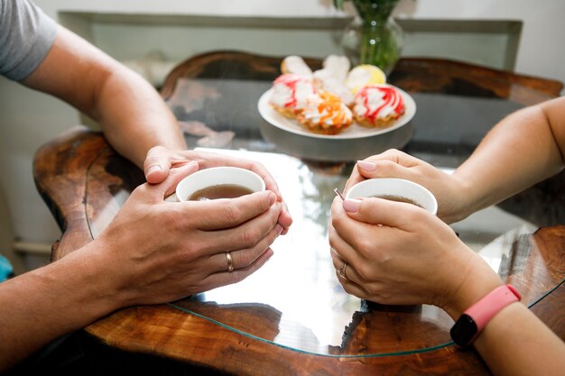 Fondo romántico, dos tazas de café y manos de pareja enamorada en fecha. Cena romántica en san valentín