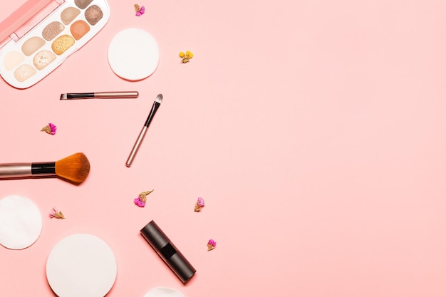 fondo rosa con cosméticos decorativos y herramientas como pinceles de lápiz labial almohadillas de algodón en polvo