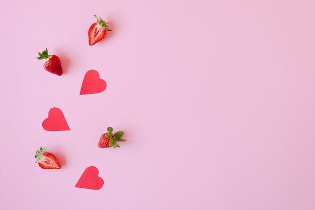 Fondo rosa festivo. Corazones de papel rojo, fresas frescas. Amor. Día de San Valentín. 14 de febrero