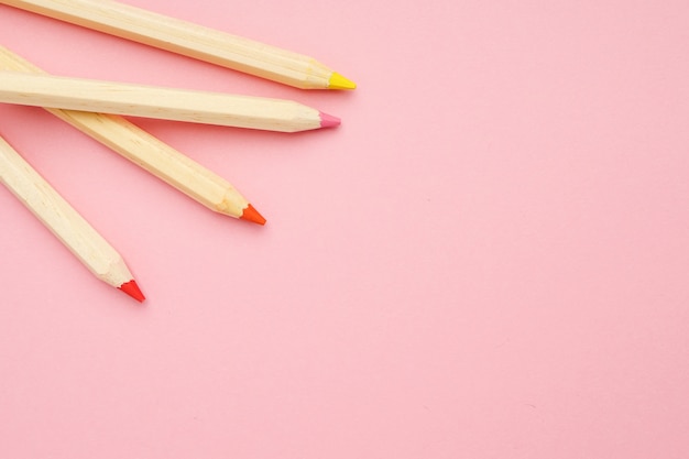 Fondo rosa con lápices de colores ordinarios de madera. De vuelta a la escuela.