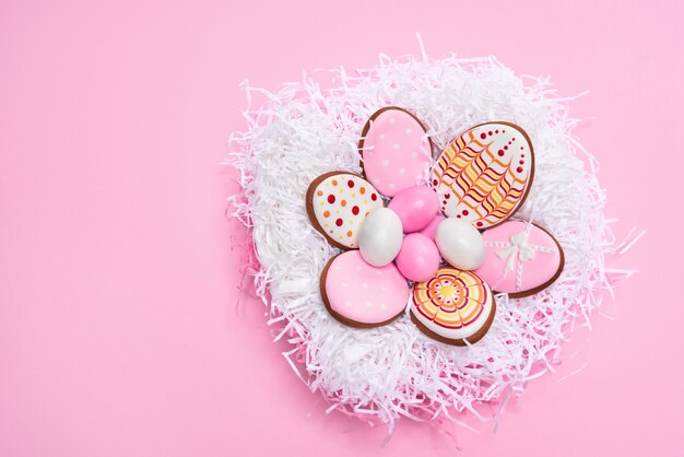 Fondo rosa pastel con huevos de pascua y sabrosas galletas